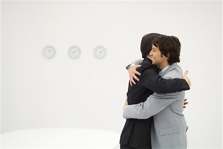 Two businessmen embracing, smiling, side view Foto de stock - Sin royalties Premium, Código: 695-03378946