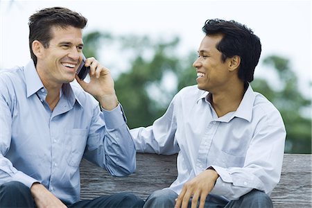 simsearch:695-03376228,k - Two men sitting on bench, smiling, one using cell phone Stock Photo - Premium Royalty-Free, Code: 695-03379012