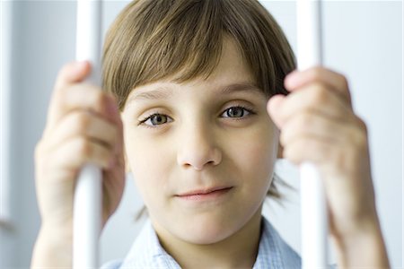 Boy behind bars, smiling at camera, portrait Stock Photo - Premium Royalty-Free, Code: 695-03379077