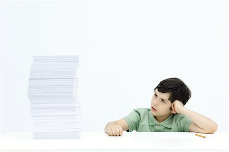 simsearch:695-03380694,k - Boy sitting at table next to tall stack of homework, frowning Stock Photo - Premium Royalty-Free, Code: 695-03379082