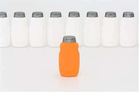 Single orange bottle in front of row of white bottles Stock Photo - Premium Royalty-Free, Code: 695-03379133