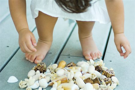 Child bending over pile of seashells, cropped view of low section Stock Photo - Premium Royalty-Free, Code: 695-03379330