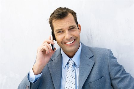 simsearch:695-03376228,k - Businessman using cell phone, smiling at camera Stock Photo - Premium Royalty-Free, Code: 695-03379391