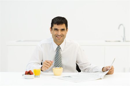 simsearch:696-03395895,k - Man sitting at breakfast table with newspaper, smiling at camera Stock Photo - Premium Royalty-Free, Code: 695-03379478