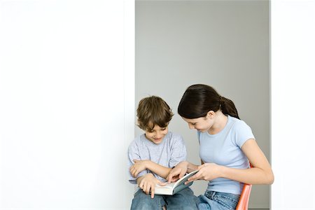 Preteen girl and little brother reading book together Foto de stock - Sin royalties Premium, Código: 695-03379506