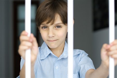 Boy behind bars, smiling at camera Stock Photo - Premium Royalty-Free, Code: 695-03379613