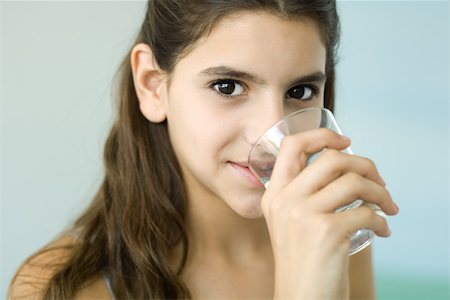 simsearch:6108-07969525,k - Teen girl drinking glass of water, smiling at camera Stock Photo - Premium Royalty-Free, Code: 695-03379867