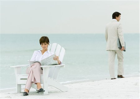 simsearch:695-03386286,k - On beach, businessman carrying laptop, walking by woman reading newspaper in chair Stock Photo - Premium Royalty-Free, Code: 695-03373576