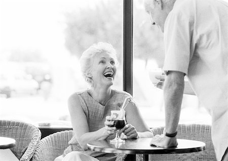 flirt senior woman - Mature woman sitting at table and looking up at mature man in a cafe, B&W Stock Photo - Premium Royalty-Free, Code: 695-03384136