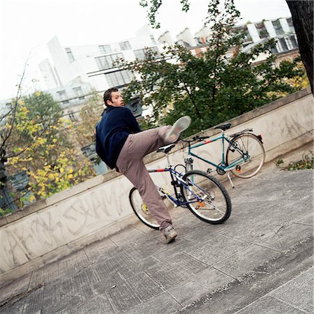 fleeing - Young man getting on bike Stock Photo - Premium Royalty-Free, Code: 695-03384735