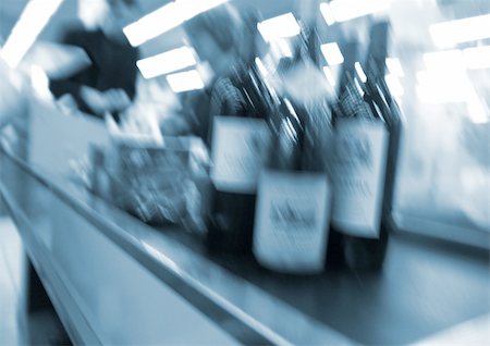 Bottles on conveyor belt at checkout counter, blurred Stock Photo - Premium Royalty-Free, Code: 695-03385300