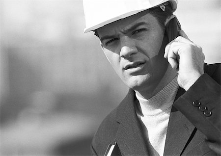 Man with hard hat using cell phone, close-up, b&w Stock Photo - Premium Royalty-Free, Code: 695-03386677