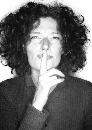 shhh - Woman smiling, finger over mouth, portrait, b&w. Stock Photo - Premium Royalty-Free, Code: 695-03387189