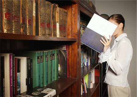 ruffle (gathered pleats) - Young woman taking book from bookshelf Stock Photo - Premium Royalty-Free, Code: 695-03387240