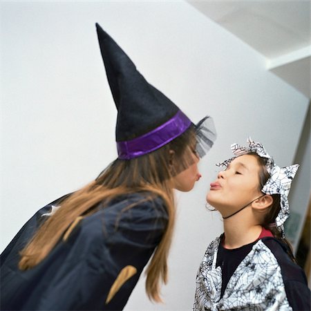 Two girls wearing costumes, sticking out tongues at each other Stock Photo - Premium Royalty-Free, Code: 695-03387275