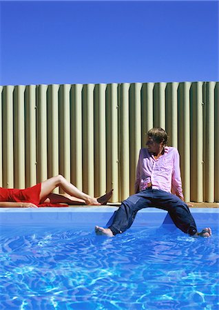 Man and woman relaxing by swimming pool, man dipping feet in water Stock Photo - Premium Royalty-Free, Code: 695-03387596