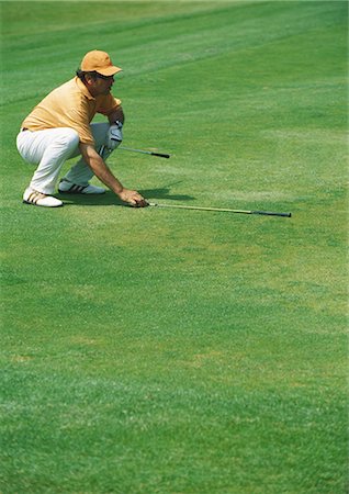 simsearch:6113-07159316,k - Golfer crouching on green, pointing golf club Stock Photo - Premium Royalty-Free, Code: 695-03388223