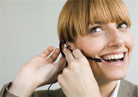 switchboard operator - Woman smiling and putting on headset Stock Photo - Premium Royalty-Free, Code: 695-03388383