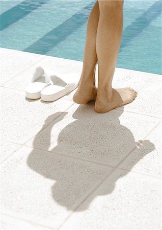 Woman standing by edge of pool, rear view of legs Stock Photo - Premium Royalty-Free, Code: 695-03388396