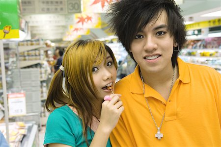 simsearch:693-06013903,k - Teenage couple in grocery store, girl eating lollipop Stock Photo - Premium Royalty-Free, Code: 695-03388897