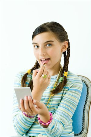 Preteen girl putting on lipstick, looking at camera Stock Photo - Premium Royalty-Free, Code: 695-03389230