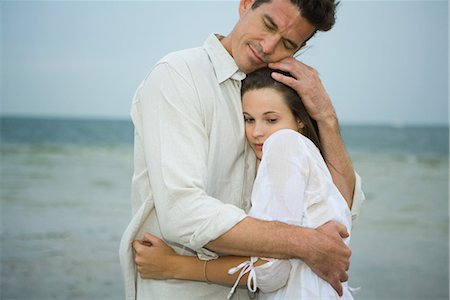 Man and teen girl hugging on beach, waist up Stock Photo - Premium Royalty-Free, Code: 695-03389528