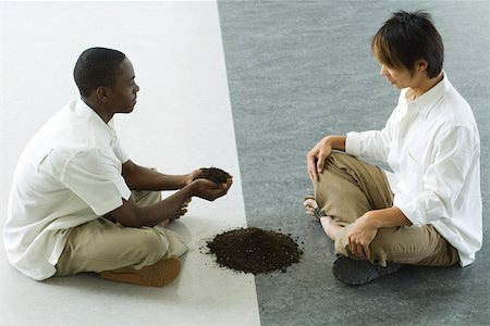 Two males sitting face to face, one holding out handful of soil Foto de stock - Sin royalties Premium, Código: 695-03389756