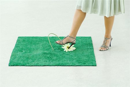 Woman sticking heel into flower on square of artificial turf, low section Stock Photo - Premium Royalty-Free, Code: 695-03389757