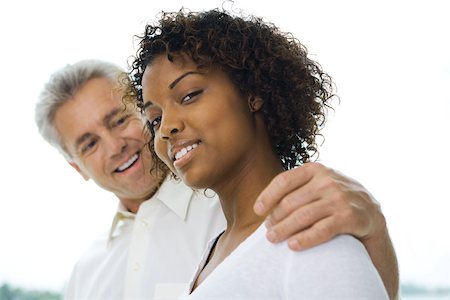 Man with arm around woman's shoulder, woman smiling at camera, side view Stock Photo - Premium Royalty-Free, Code: 695-03389771