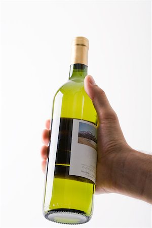 Hand holding up bottle of white wine Stock Photo - Premium Royalty-Free, Code: 695-03389896