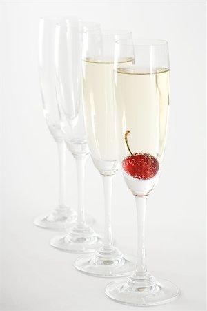 simsearch:6118-07354031,k - Champagne flutes, two filled with champagne, one with a cherry floating in it Stock Photo - Premium Royalty-Free, Code: 695-03389899