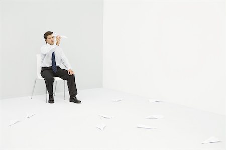 slacker - Young professional man sitting in corner, throwing paper airplanes Stock Photo - Premium Royalty-Free, Code: 695-03389922