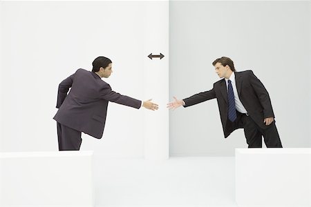 Two businessmen reaching to shake hands, arrow between them Stock Photo - Premium Royalty-Free, Code: 695-03389937