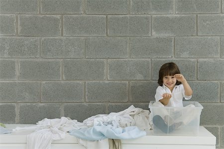 simsearch:695-05768235,k - Little boy sitting in plastic storage container, laundry strewn beside him, pretending to drive Stock Photo - Premium Royalty-Free, Code: 695-03389969