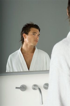 Man looking at himself in mirror, wearing bathrobe, head tilted Stock Photo - Premium Royalty-Free, Code: 695-03380057