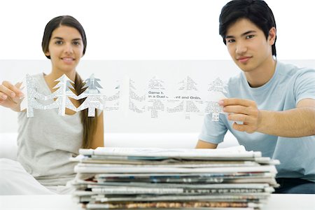 reuse - Two young adults holding tree shapes cut out of newspaper, smiling at camera Stock Photo - Premium Royalty-Free, Code: 695-03380094