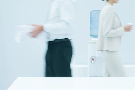 productivity - Colleagues walking in front of water cooler, blurred side view Stock Photo - Premium Royalty-Free, Code: 695-03380269