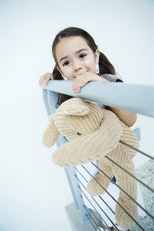 simsearch:649-06623087,k - Little girl standing at rail holding teddy bear, smiling at camera Stock Photo - Premium Royalty-Free, Code: 695-03380426