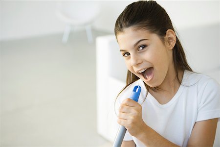 Girl holding broom handle, pretending to sing into microphone Stock Photo - Premium Royalty-Free, Code: 695-03380618