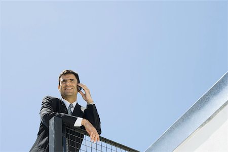 simsearch:695-03376228,k - Businessman leaning against railing, using cell phone, low angle view Stock Photo - Premium Royalty-Free, Code: 695-03380634