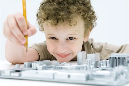Little boy holding pencil over computer motherboard, smiling at camera Stock Photo - Premium Royalty-Free, Code: 695-03380688