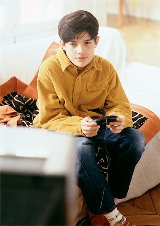simsearch:632-03424261,k - Boy playing video games on couch. Stock Photo - Premium Royalty-Free, Code: 695-03381003