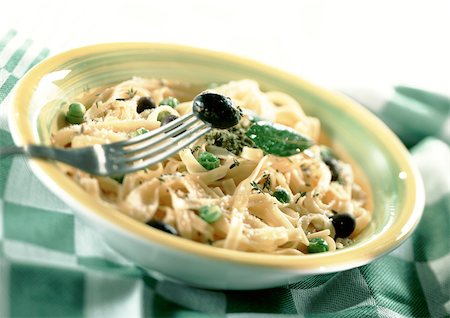 simsearch:6118-07808971,k - Fettuccini with fresh basil and black olives in bowl, on green and white checked tablecloth, close-up Stock Photo - Premium Royalty-Free, Code: 695-03381309