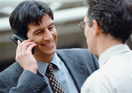 simsearch:695-03376228,k - Two businessmen, one holding cell phone, smiling Stock Photo - Premium Royalty-Free, Code: 695-03381577