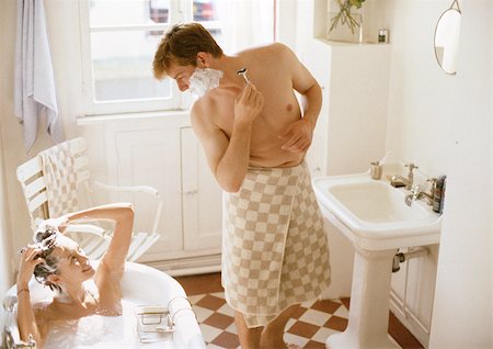 sudsy - Woman taking bath, man with towel wrapped around waist shaving, in bathroom Stock Photo - Premium Royalty-Free, Code: 695-03381794