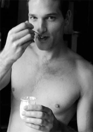 Man eating yogurt, looking at camera, b&w Stock Photo - Premium Royalty-Free, Code: 695-03382056
