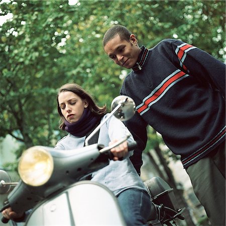 simsearch:695-03382482,k - Young man standing next to young woman on motor scooter Stock Photo - Premium Royalty-Free, Code: 695-03382485