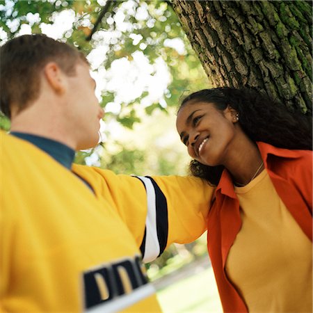 simsearch:695-03382482,k - Young woman leaning against tree looking up at young man Stock Photo - Premium Royalty-Free, Code: 695-03382482