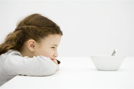 simsearch:695-03380694,k - Little girl sitting at table with head resting on arms, staring at bowl, side view Stock Photo - Premium Royalty-Free, Code: 695-03390113