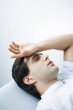 Man reclining with eyes closed, hand on forehead Stock Photo - Premium Royalty-Free, Code: 695-03390126